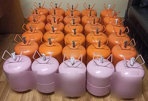 Eine Reihe von orangefarbenen und lila Gasflaschen ist ordentlich aufgereiht.