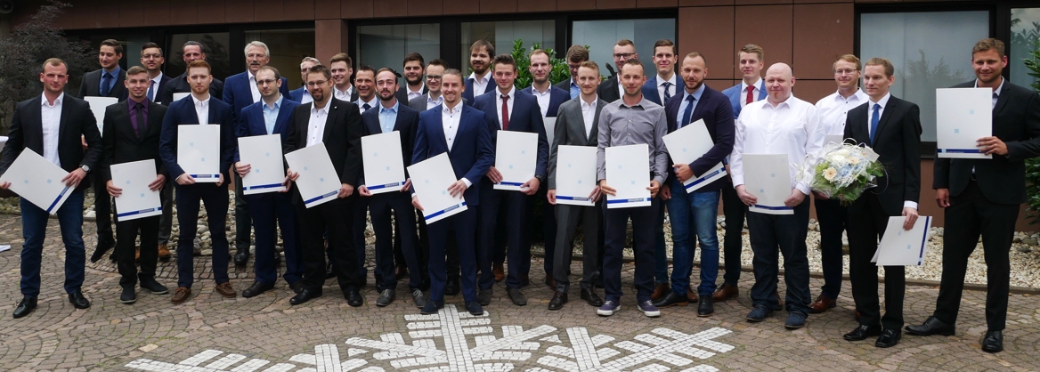 Gruppe von Menschen steht in Reihen und hält Zertifikate, während sie lächeln und feiern.