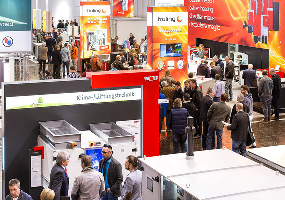 Ein belebter Messestand mit Menschen, die sich um technische Geräte und Informationsstände versammeln.