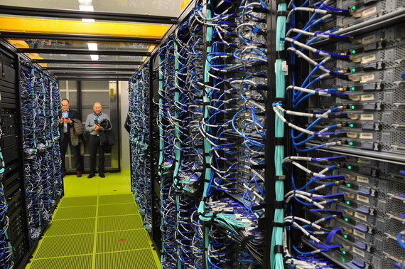 Zwei Personen stehen in einem großen Serverraum mit Reihen von Serverregalen und Kabeln.