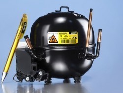 Ein schwarzer Kühlmotor mit Warnetikett und mehreren Kabeln, neben dem eine gelbe Stiftspitze zu sehen ist.