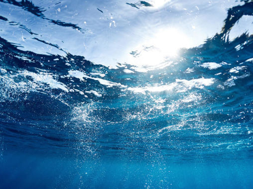 Unterwasseransicht mit Sonnenstrahlen, die durch die Wasseroberfläche brechen.