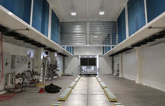 Innenansicht eines großen, hell erleuchteten Hallenraums mit blauen Wänden, einer Laufbahn und Sportgeräten.