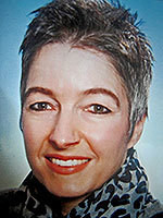 Eine Person mit kurzem Haar und einem Schal lächelt in die Kamera.