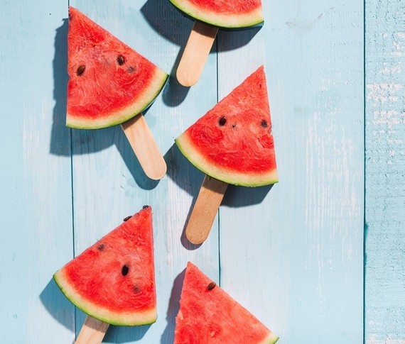 Ein Bild von Wassermelonen-Schnecken auf Stäbchen, die auf einem hellblauen Holzuntergrund angeordnet sind.