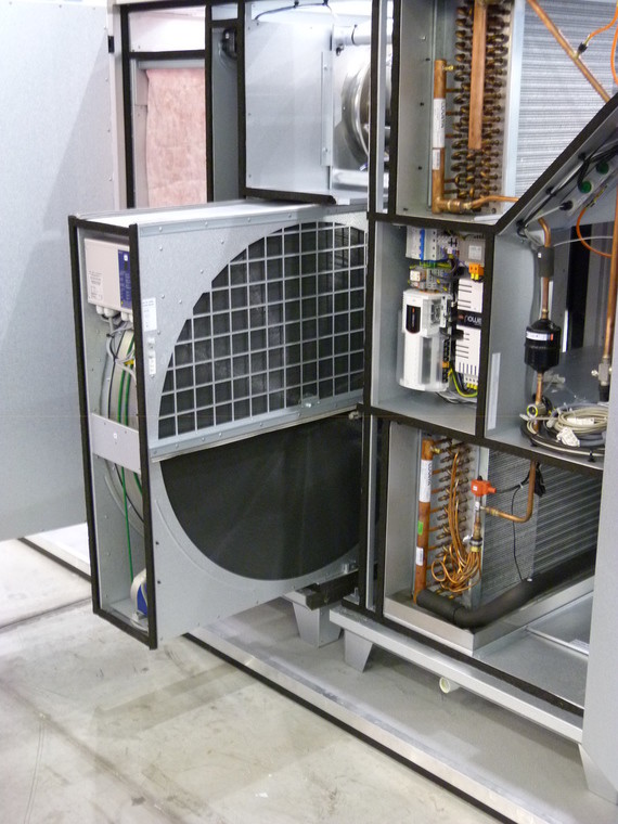 Ein technisches Gerätegehäuse mit offener Tür, das verschiedene Komponenten wie Rohre, Kabel und elektronische Bauteile enthält.