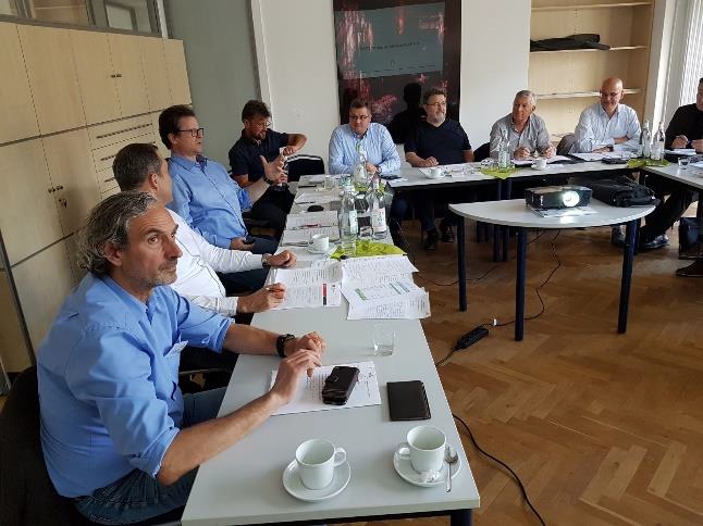 Eine Gruppe von Menschen sitzt an Tischen in einem Besprechungsraum und diskutiert.