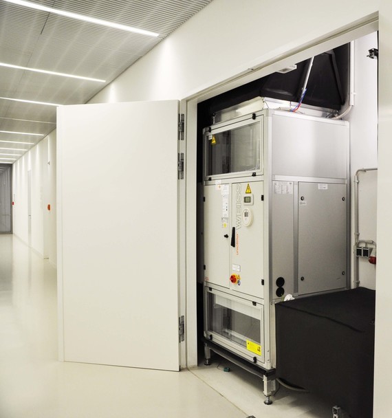 Ein Bild von einem technischen Gerät in einem sauberen, hellen Raum mit offener Tür und einem Gang im Hintergrund.