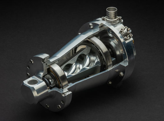 Ein glänzendes, mechanisches Bauteil mit einem komplexen Inneren, das auf einem dunklen Hintergrund präsentiert wird.