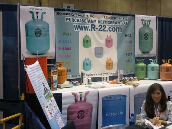 Ein Stand mit Kühlmitteldosen und einem Banner, das Informationen über Kühlmittel wie R-22 und R-404A sowie Preise anzeigt.