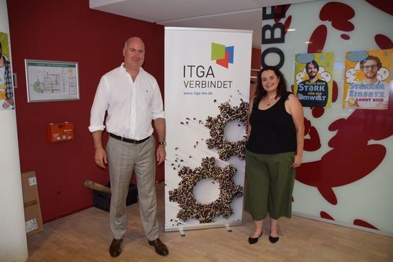 Zwei Personen stehen vor einem Schild mit der Aufschrift 