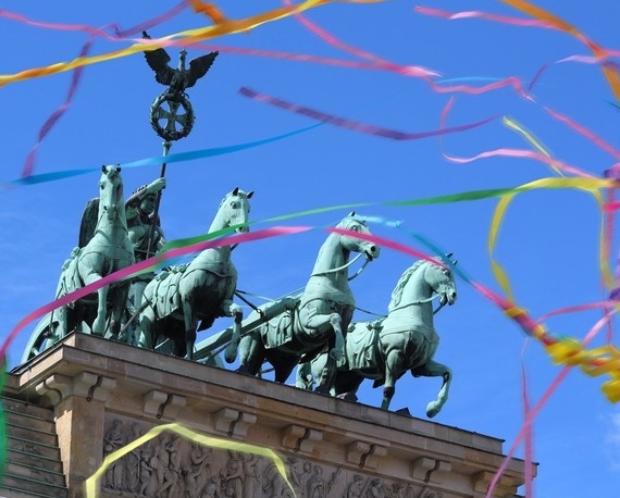 Ein Bronzefries mit vier galoppierenden Pferden und einem Adler auf einem Sockel, umgeben von bunten Girlanden.
