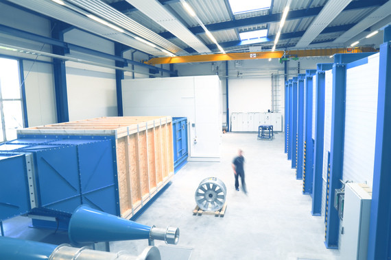 Ein 3D-Modell eines Lagerhauses mit blauen Regalen, einer Person, die einen Gabelstapler bedient, und einer hohen Decke mit Metallträgern.