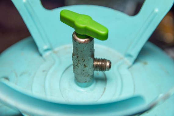 Ein grüner Knopf ist auf einem blauen Metallgestell befestigt, das auf einer weißen Unterlage steht.