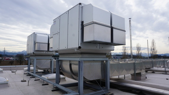 Zwei große, rechteckige Klimaanlagen stehen auf einem Dach, umgeben von einer städtischen Landschaft.