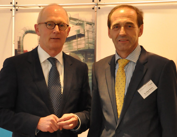 Zwei Männer in Anzügen stehen nebeneinander und lächeln in die Kamera.