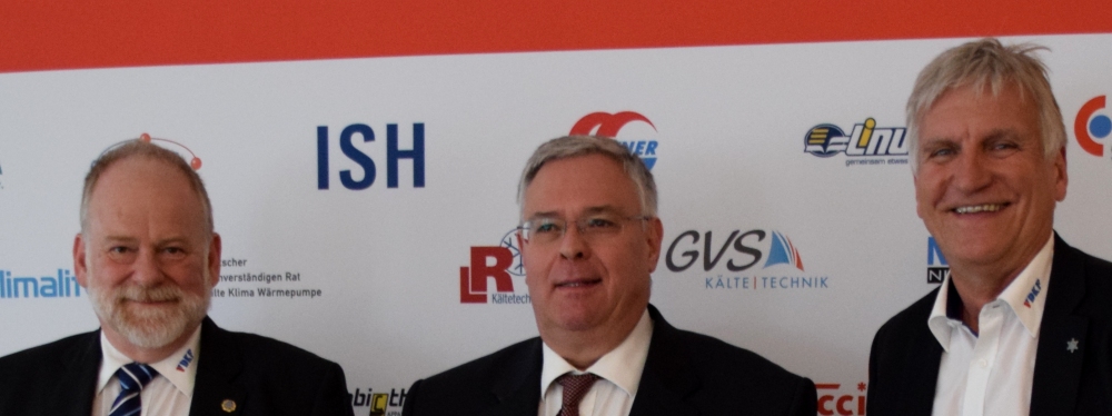 Drei Männer stehen nebeneinander vor einem Hintergrund mit Logos von ISH, GVS und anderen Firmen.