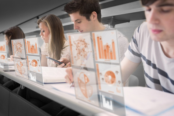 Vier Personen sitzen in einer Reihe und arbeiten an Computern mit grafischen Darstellungen auf den Bildschirmen.