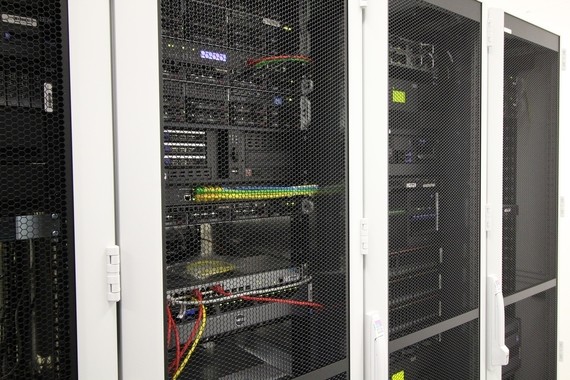 Drei Serverracks in einem Serverraum mit Netzwerkkabeln und elektronischen Komponenten.