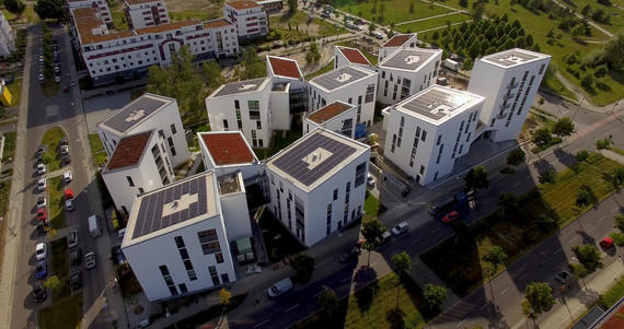 Eine 3D-Ansicht von mehreren modernen Wohngebäuden mit flachen Dächern und gepflasterten Straßen im Vordergrund.