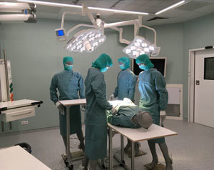 Eine Gruppe von medizinischen Fachkräften in OP-Kleidung steht um einen Patienten herum, der auf einem OP-Tisch liegt.