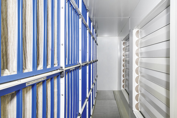 Ein Lager mit blauen Metallschränken und weißen Regalen, die mit verschiedenen Gegenständen gefüllt sind.