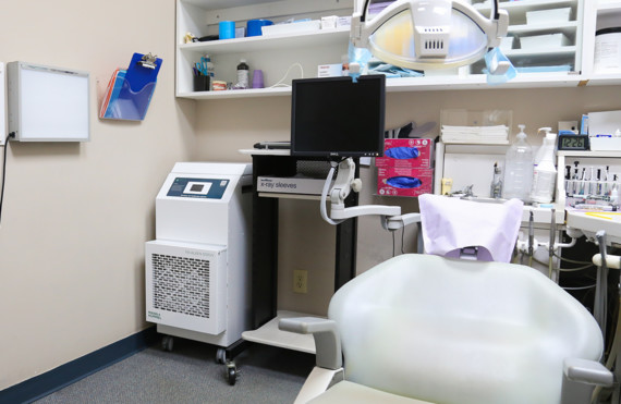 Ein medizinisches Behandlungszimmer mit Stuhl, Monitor, medizinischen Geräten und Ausrüstung.