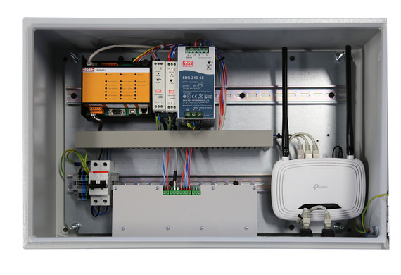 Ein elektronisches Schaltschrankgehäuse mit verschiedenen Komponenten wie Netzteil, Relais, Kabel und Sicherungen.