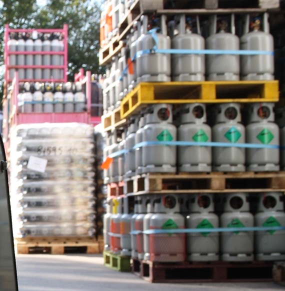 Viele Gasflaschen sind auf Paletten gestapelt und mit blauen Banden gesichert.
