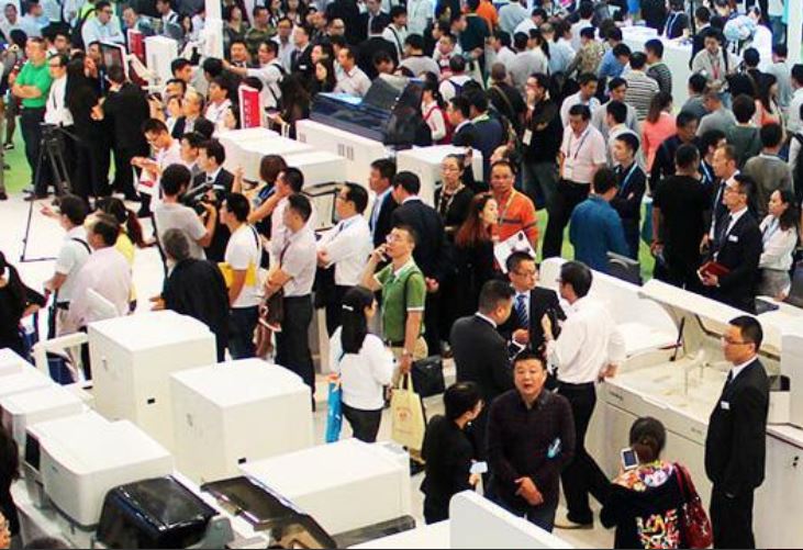 Ein belebter Veranstaltungsort mit vielen Menschen, die an verschiedenen Tischen stehen und sich unterhalten.