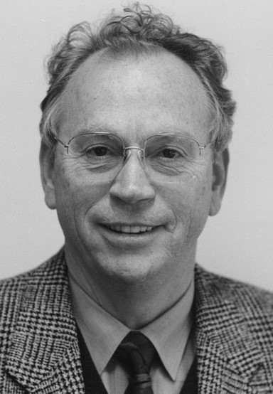 Ein Mann mit Brille und einem karierten Hemd lächelt in die Kamera.