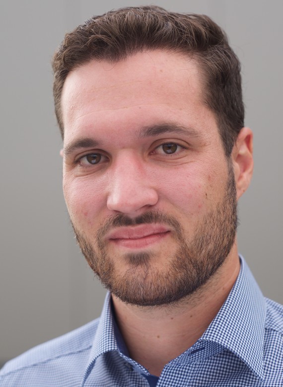 Ein Mann mit dunklem Haar und Bart trägt ein kariertes Hemd.