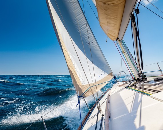 Ein Segelboot fährt auf ruhigem Meer unter klarem blauen Himmel.