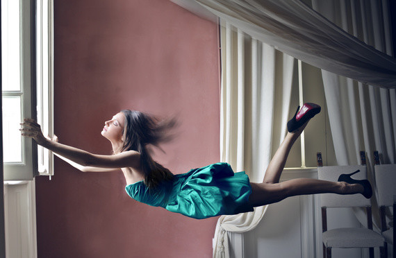 Eine Person in einem grünen Kleid führt eine elegante Tanzbewegung in einem eleganten Raum aus.