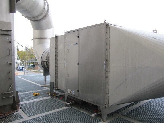 Ein großes, rechteckiges Metallkasten-Gerät mit Rohren und einem Metallgitterboden im Hintergrund.