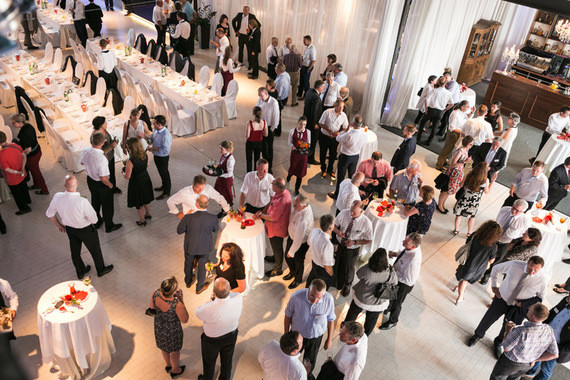 Eine Gruppe von Menschen feiert in einem eleganten Saal mit gedeckten Tischen und Beleuchtung.