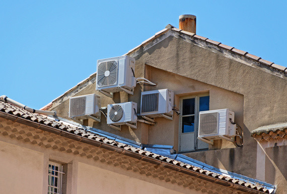 Ein Gebäude mit mehreren Klimaanlagen auf dem Dach und an der Fassade.