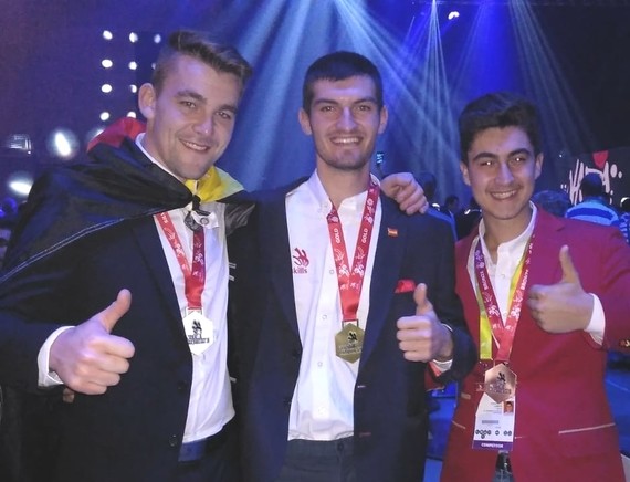 Drei Personen mit Medaillen stehen nebeneinander und zeigen Daumen hoch.