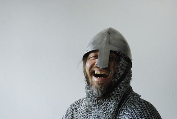 Ein lachender Mensch in mittelalterlicher Rüstung mit Helm und Kettenhemd.