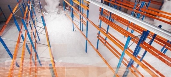 Ein Lagerregal mit orangefarbenen und blauen Metallstrukturen steht in einem hell erleuchteten Raum.