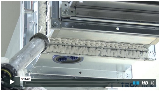 Ein Bild zeigt einen mechanischen Aufzug mit Metallteilen, einer Rolle und einem Schienen-System.