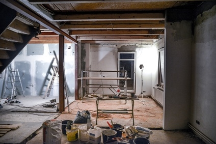 Ein Raum in Bau mit offenen Balken, einer Leiter, einem Gerüst und verschiedenen Baustoffen.