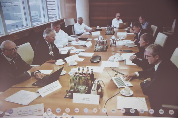 Eine Gruppe von Menschen sitzt um einen Konferenztisch herum bei einer Besprechung.