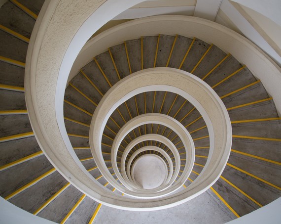 Eine spiralförmige Treppe mit gelben Streifen führt in einem geschwungenen Muster nach unten.