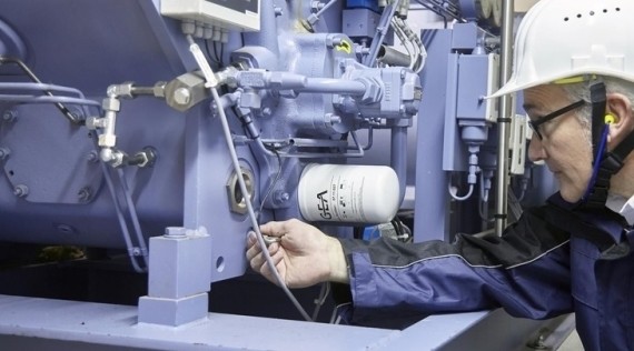 Ein Arbeiter in Schutzausrüstung repariert oder wartet an einer industriellen Maschine.