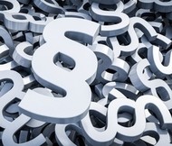 Ein Haufen silberner Paragraphensymbole (§) liegt durcheinander.