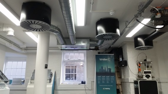 Ein modernes Büro mit hohen Decken, beleuchteten Arbeitsplätzen, einer großen Fensterfront und einer Wandtafel mit dem Logo von Siemens.