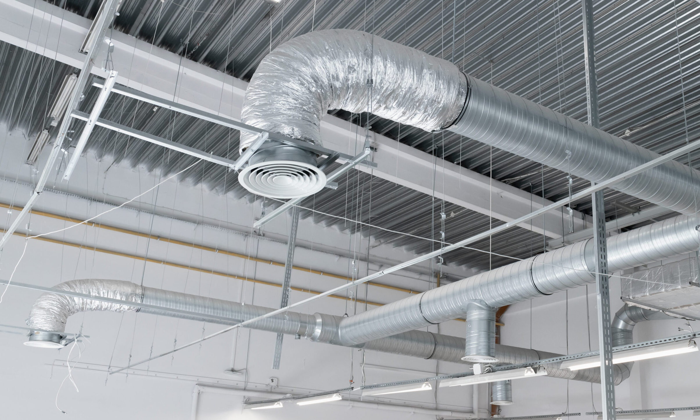 Ventilation and air conditioning system on the ceiling of an industrial building, metal ventilation pipes